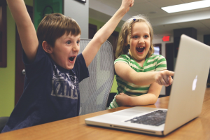 Du vaikai žiūri į kompiuterį