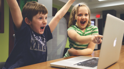 Du vaikai žiūri į kompiuterį
